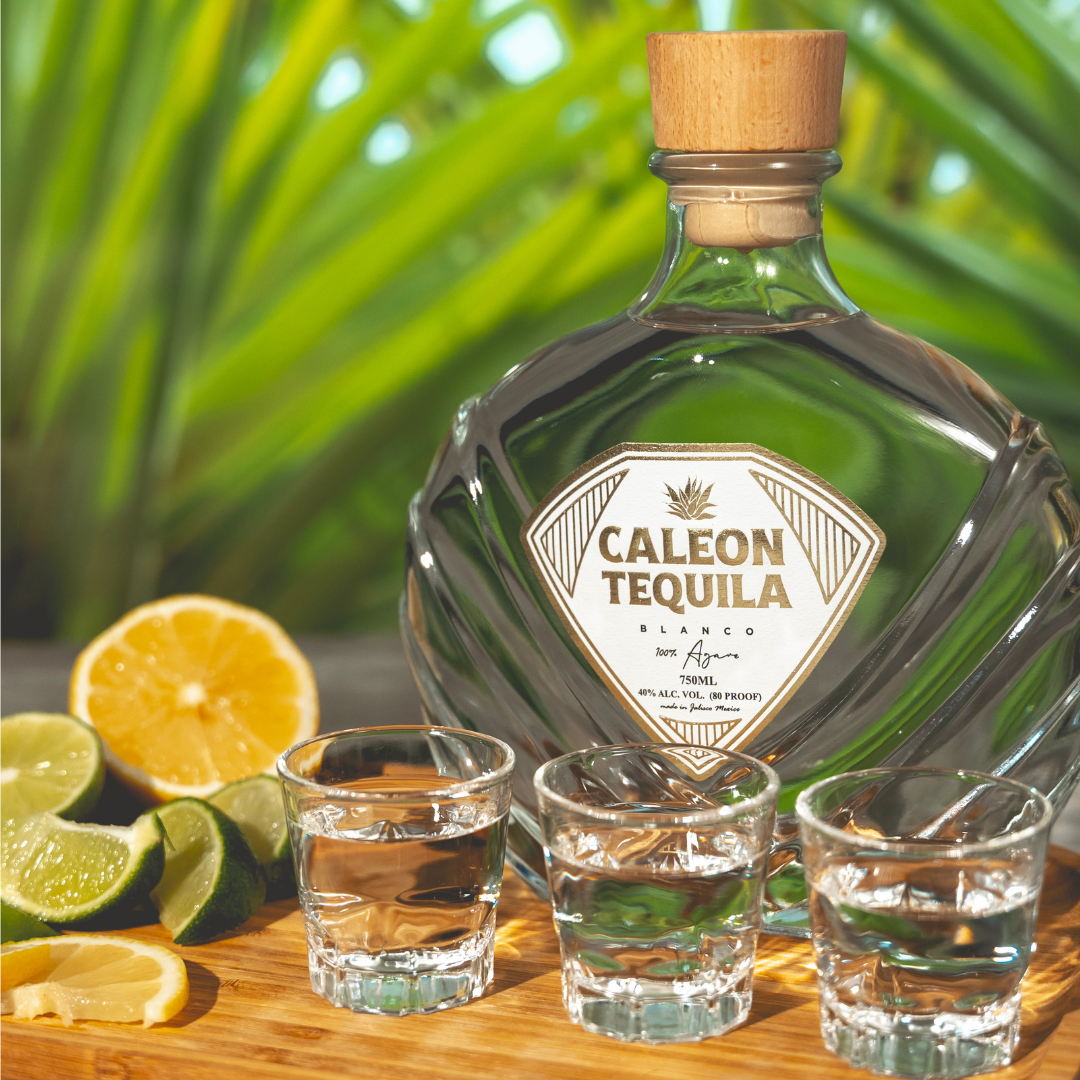 Caleon Tequila Blanco bottle with shot glasses, fresh limes, and lemons in a sunny setting